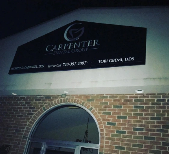 Carpenter Dental Group storefront sign mounted on brick building exterior at night.