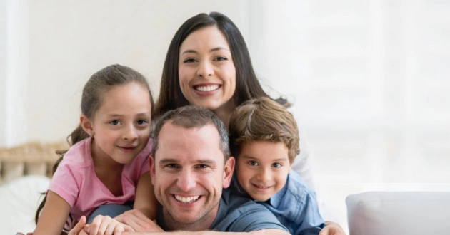 Happy family of four smiling together indoors at dental office