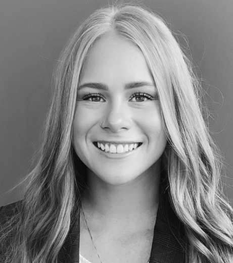 Professional headshot of smiling woman with long blonde hair against gray background for dental practice.